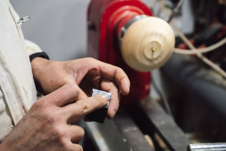 A woodworker applying glue to a small piece of wood in his workshopの写真素材