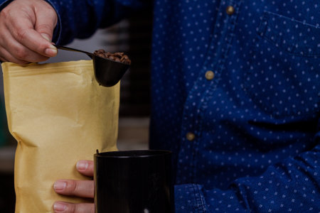 A closeup shot of a Hispanic man holding a spoon of coffee beansの写真素材