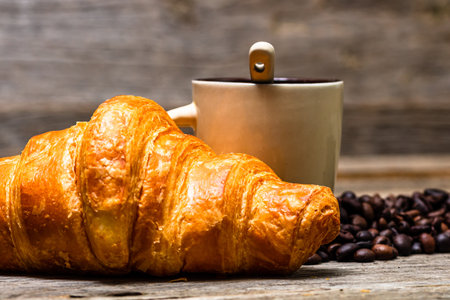 A closeup shot of freshly baked golden brown French croissant with coffeeの写真素材