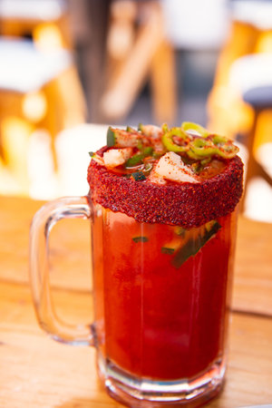 A closeup of a fresh Mexican spicy Michelada drink in a salt-rimmed glass