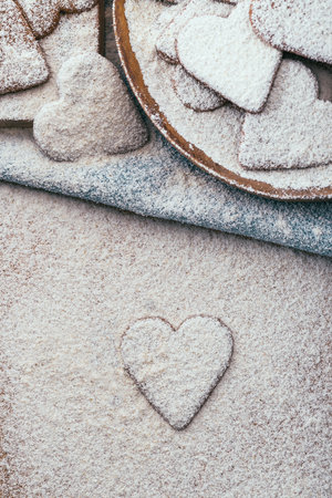 Freshly baked heart shaped cookies covered in icing sugar for valentine's day on a wood plate and a blue tableclothの写真素材