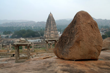 A pyramid shaped rock and a matching shape temple tower in Hampi, Karnataka, India, Asiaの写真素材