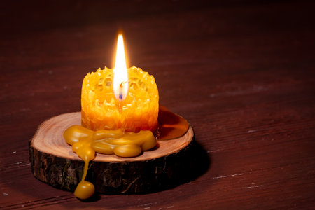 A closeup of a burning candle on a small wooden log pieceの写真素材