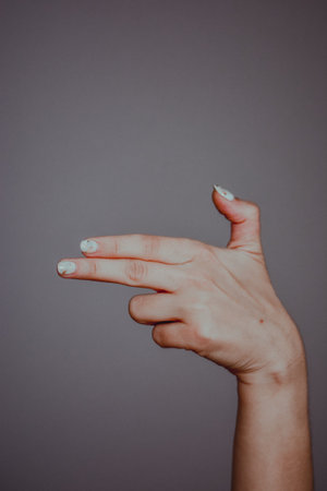 A vertical shot of a female hand pointing to the right isolated on gray backgroundの写真素材
