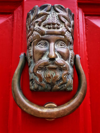 Closeup of decorative bronze door knocker made in the shape of a male head on Georgian red door of an Irish house in Dublin, Ireland.の写真素材