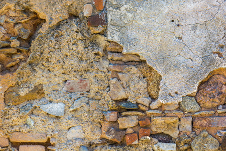An old semi-destroyed stone wall textured background made of different stones