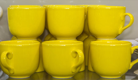 A closeup shot of yellow mugs on a shelfの写真素材
