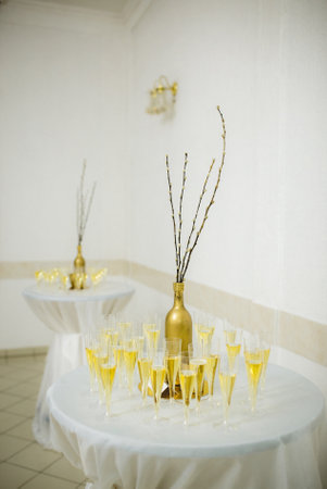 A vertical shot of a golden champagne bottle with glasses on a tableの写真素材