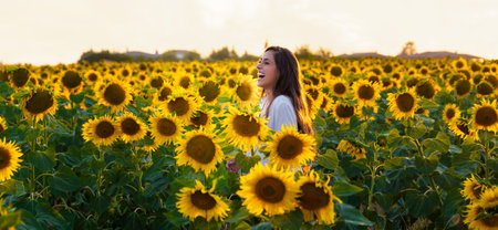 A young Spanish woman happily smiling in the sunflower fの写真素材