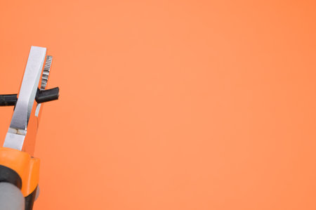A closeup shot of pliers and a wire on a colorful background