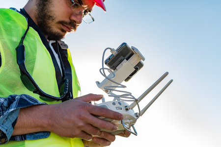 A low angle of a Caucasian male holding a remote controller of a drone on background of the skyの写真素材