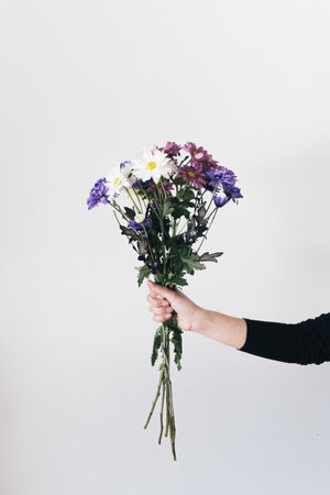 A vertical shot of woman's hand holding the flower composition bouquet isolated in white background.の写真素材