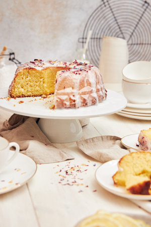 A delicious citron cake with glaze and flower on top on a white tableの写真素材