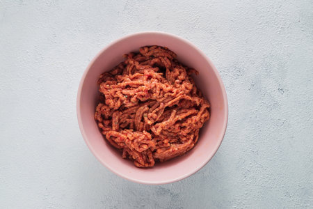 A top view of raw ground meat in a bowl on a white surfaceの写真素材