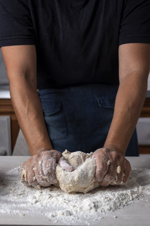 A vertical shot of a baker kneading dough in the kitchenの写真素材
