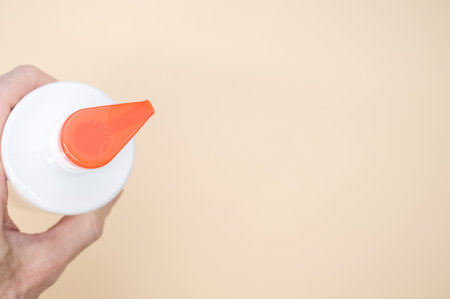 A top view of hand holding pump plastic bottle container isolated on pastel backgroundの写真素材