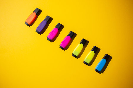A top view of multicolored markers on a yellow work tableの写真素材
