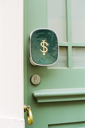 A vertical shot of the dollar sign on the handle of a green door