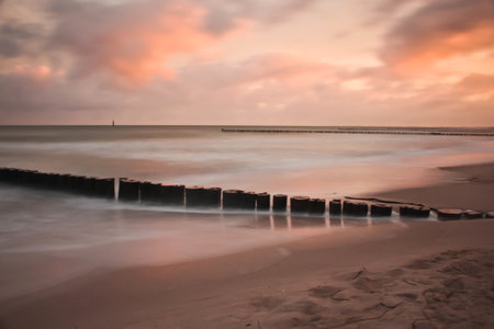 A breakwater in the sandy beach during the sunset