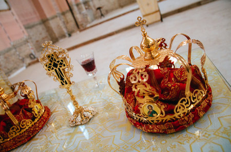 A high angle shot of crowns and a cross with a glass of wine - wedding conceptの写真素材