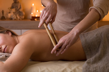 An attractive Spanish woman getting a relaxing massage with bamboo sticks in a wellness centerの写真素材