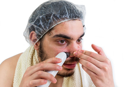 A closeup shot of a young Jewish man removing blackheads on his nose