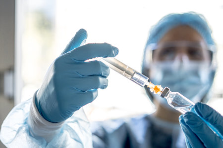 A medical worker holding the Covid-19 vaccine with a syringeの写真素材