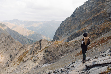 A beautiful female standing on a high rocky formation and observing the view
