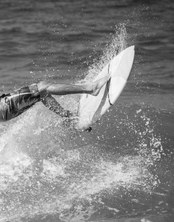 A grayscale shot of a person surfing on the wavesの写真素材