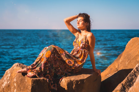 A young brunette with wet hair and a floral dress by the seaの写真素材