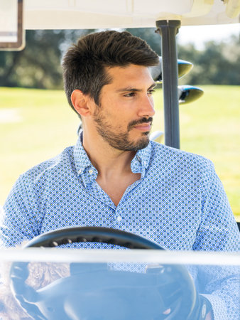 A young Caucasian male in a golf cart on a professional golf courseの写真素材