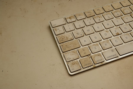 A closeup shot of a weathered dirty keyboard on a dirty white surfaceの写真素材