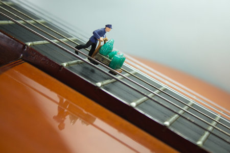 A closeup shot of a small figure of a person on a classical guitarの写真素材