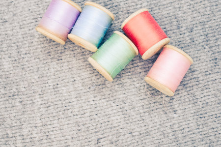 A colorful sewing threads on top of a grey fabric with free space for text