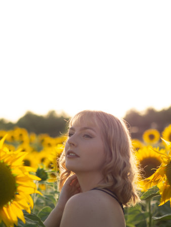 A portrait of a Spanish young female relaxing in the summer sunflower fieldの写真素材