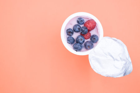 A berry yogurt in a plastic cup on an orange backgroundの写真素材