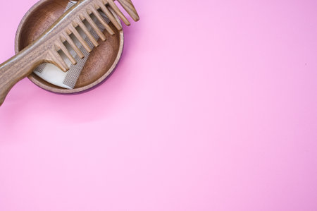 A top view of hairbrushes in a wooden bowl on a pink backgroundの写真素材