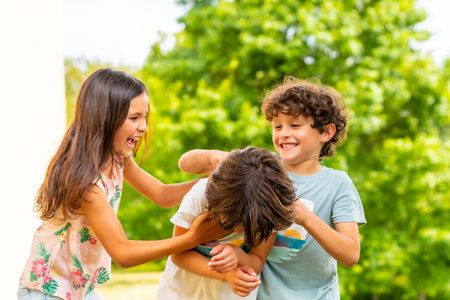Lifestyle of three brothers smiling and playing together in a park, friends and brothers enjoying as a family, tickling each otherの写真素材