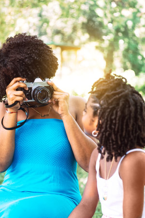 portrait of a woman with afro taking a picture of a little girl. concept photography and learning.の写真素材
