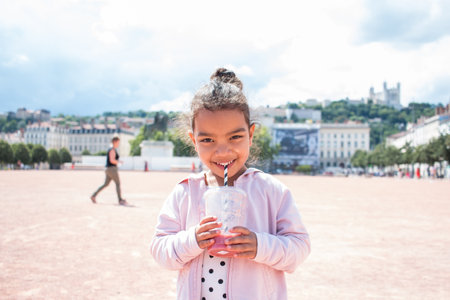 A little girl drinking juice in the city enjoying the summerの写真素材