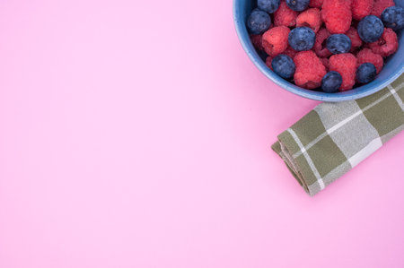 A bowl of fresh blueberries and raspberries isolated on a pink backgroundの写真素材