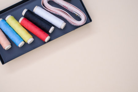 A pack of colorful sewing threads and a measuring tape on a clear background with a copy space