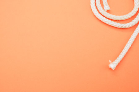 a top view of a white spiral rope on the pastel orange background on the right sideの写真素材