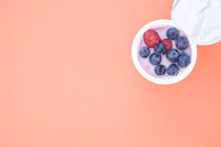 A berry yogurt in a plastic cup on an orange backgroundの写真素材