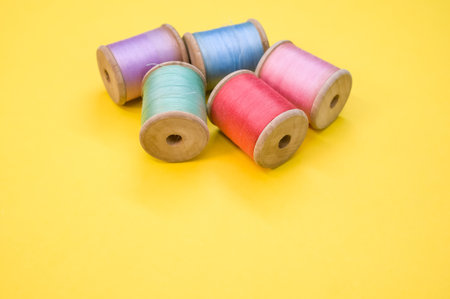 A colorful sewing threads isolated on a yellow background with free space for text