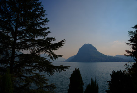 Dusk on the Lakefront with Mountain Peak San Salvatore and Trees in Lugano, Switzerland.の写真素材