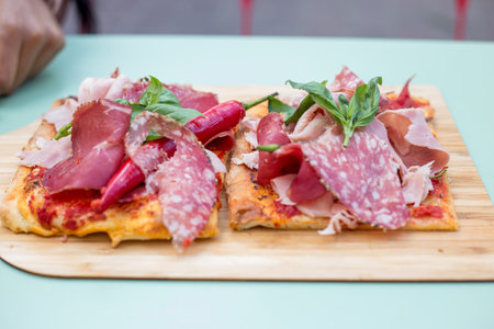 A closeup shot of a pizza with sausages on a wooden board on a blurred backgroundの写真素材