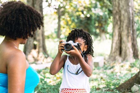 a little girl taking a photograph with an old camera of a woman. childhood conceptの写真素材