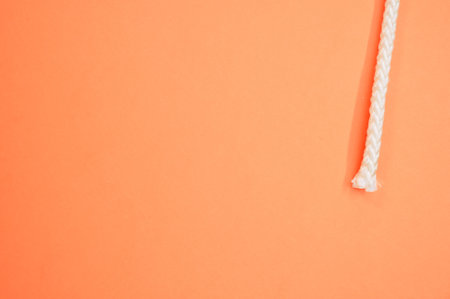A closeup of a rope end isolated on peach backgroundの写真素材