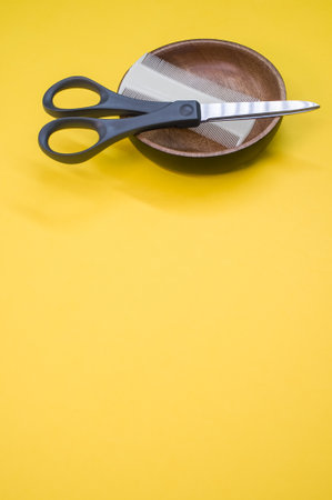 A closeup shot of scissors and hair comb on a yellow surface - copy spaceの写真素材